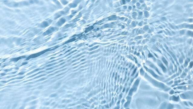 Multiple waves of water cross each other creating ripples spontaneously on pale blue background | Beauty background shot for skin care cosmetics advertisement