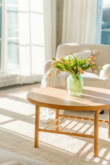 A bouquet of tulips in a beautiful vase at home in a bright modern interior on a wooden table. Spring concept