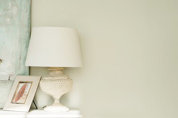 Detail of a bright modern room with a white lamp on the chest of drawers and an empty wall for your text
