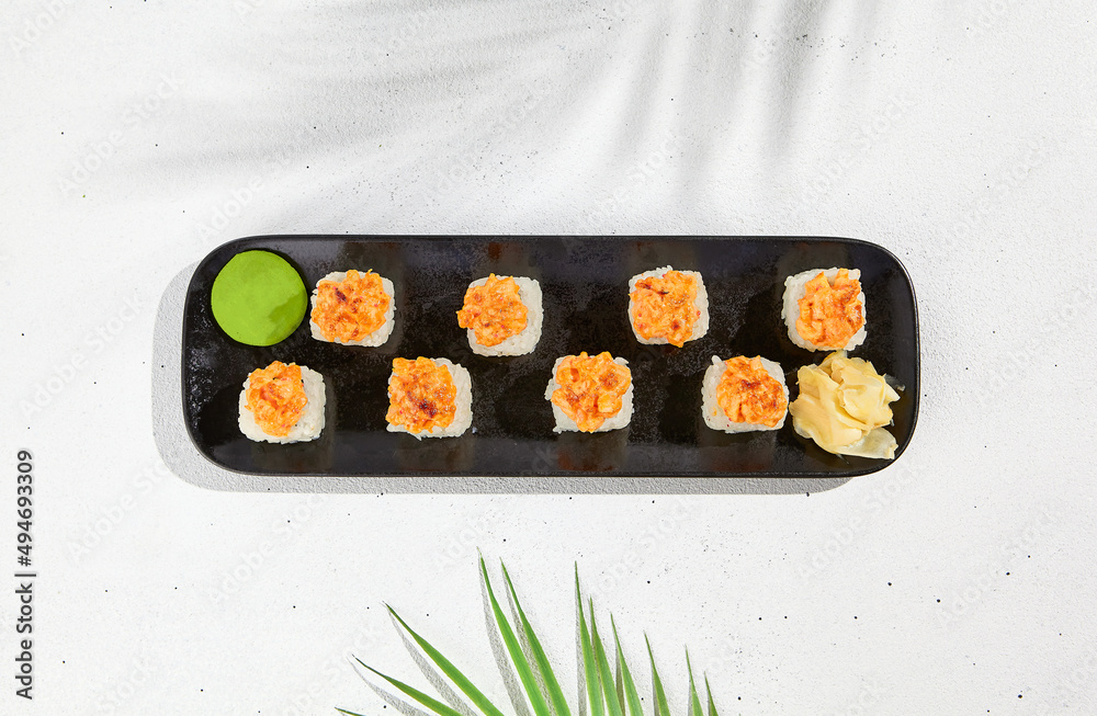 Sticker Maki sushi with salmon top on black plate. Sushi roll with philadelphia cheese inside and salmon tartare outside. Maki roll in minimal concept. Summer menu for japanese restaurant.