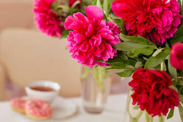 Client place in hairdressing beauty salon with cup of tea, donuts and peonies flowers
