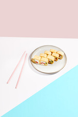 Mexican maki roll with chicken, paprika and cucumber inside, tortilla outside. Alternative sushi roll on coloured backdrop. Sushi menu concept. Maki sushi with chicken in minimal style
