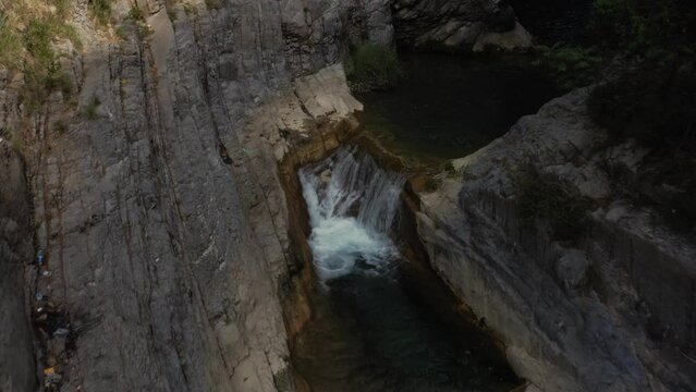 Aerial view of a water flowing into the river in between the mountains 