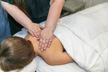 Close up of a female message therapist giving a woman a shoulder massage at a local spa