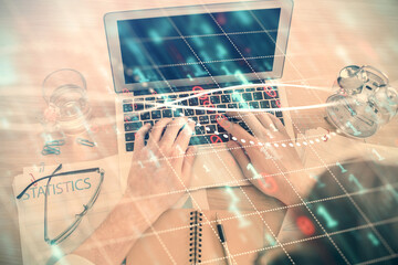 Double exposure of man's hands typing over laptop keyboard and forex chart hologram drawing. Top...