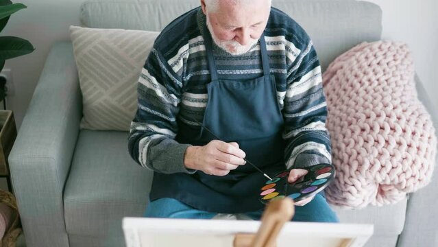 Retired senior artistic couple spends their free time drawing on canvas in the living room