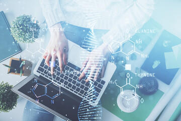 Double exposure of woman hands working on computer and DNA hologram drawing. Top View. Medical...