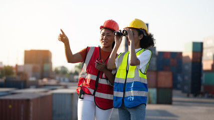 Woman foreman or engineer using binoculars and partner pointing at problem focus cargo container tank at the warehouse container logistic transportation business concept