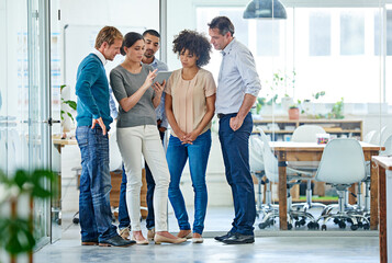 Obraz premium Sharing her ideas with the team. Shot of a group of office colleagues having a discussion over a digital tablet.