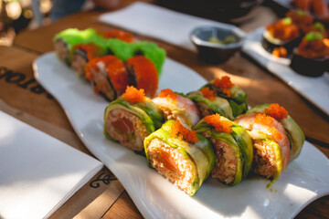 Close up of gourmet sushi rolls with salmon, masago (fish eggs), avocado, octopus and nori in a white plate