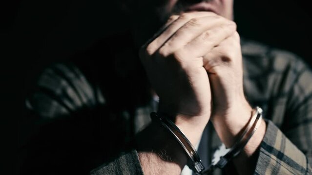 Scared man in handcuffs interrogated by police, investigation, interrogation
