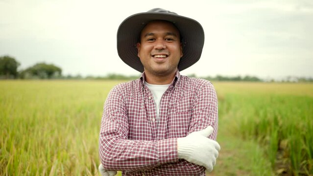 Smart farmer standing and smiling proud of their produce in rice field after harvest with sunlight. Happy man agriculture of food industry. Healthy food.