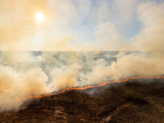 Drone photo of wildfire in the countryside. Fire spreading through dry grass quickly, burning everything on its way