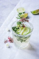 making cocktails in glasses with lime and herbs on stone kitchen desk background
