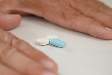 Colored pills forming small male genitalia in the hands of a man on a neutral background. Male impotence treatment concept.