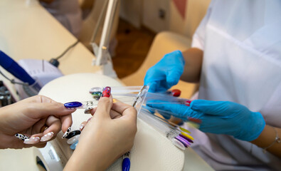 Fototapeta na wymiar Nail technician makes nail extensions gel in the beauty salon. Professional care for hands.