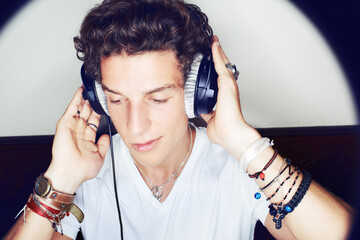 Rocking to the beat. Close up shot of a young man grooving to some music on a set of headphones surrounded by a halo of light.