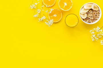 food for healthy breakfast with granola and fresh orange juice on bright yellow background top view mock up