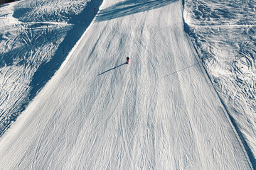 Beautiful alpine winter landscape with a lonely ski driver on a very wide slope at Maria Alm,...