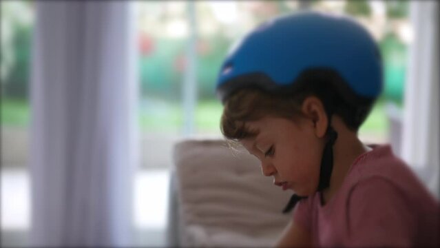 Thoughtful child wearing bike helmet indoor concentrated