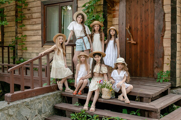 Tween girls posing together on doorstep of wooden country house in summer