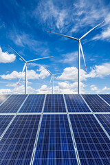 Solar panels and wind turbines landscape under blue sky. Green energy concept.