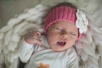 A newborn baby in a white bodysuit and denim shorts sleeps and yawns on a white blanket. Happy...