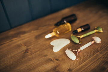 Fototapeta na wymiar Jade rollers and face massagers and natural oil in bottles on wooden background. Skin care.