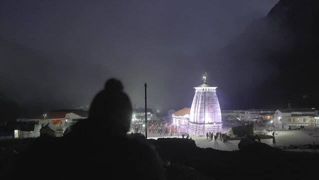 Man Walking Towards Illuminated Kedarnath Temple At Himalayan Range In Uttarakhand, India. Slow Motion