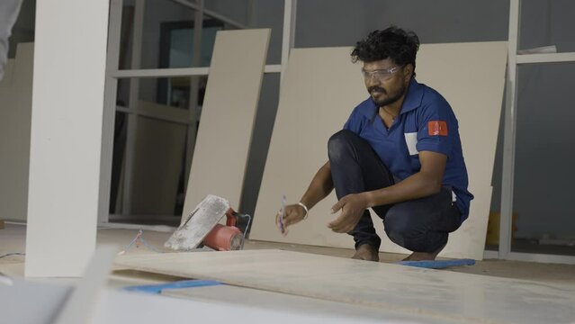 aluminium worker marking wood for design and renovation work at construction site - concept of skilled ocupation, blue collar jobs and home or office improvement.