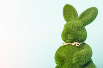 A toy green Easter bunny with artificial fur on a blue background.