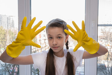 girl in yellow house gloves cleans the window of the house. Cleaning concept.