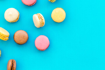 Brignt macarons for sweet break on blue background top view mock up