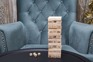 Pyramid built from wooden blocks of light wood and several game dice on a black iron table in a...