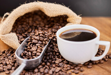 I like my coffee fresh and strong. Shot of coffee beans and a cup of black coffee on a wooden table.