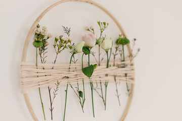 Stylish spring wreath with beautiful fresh flowers. Wooden hoop with flowers and thread hanging on...