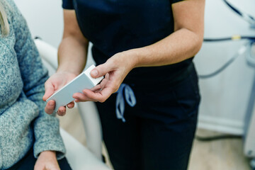 A nurse practitioner at a medical wellness spa showing an anti-aging skincare product to the patient or client