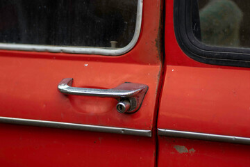 Fototapeta na wymiar gray metal handle on the red door of an old car