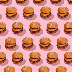 Creative burger pattern with beef patty, camembert and cherry on a pink background. minimal style