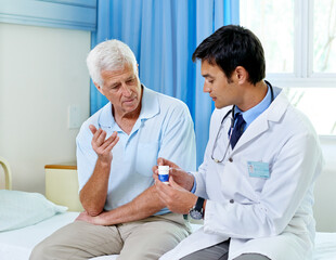 Just take one a day. Shot of a handsome young doctor explaining medication to a senior patient.