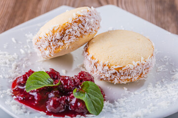 cookies filled with milk and coconut delicacy, with red fruit sauce