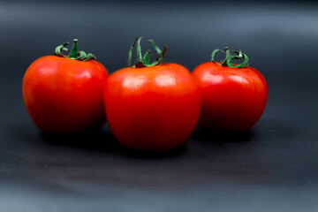 Red three Tomatoes on a dark background. Red Tomato and Black Background 