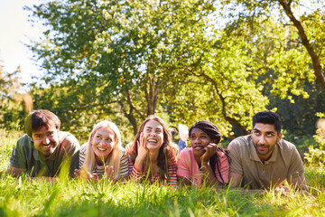 Group of friends lies together on meadow in summer