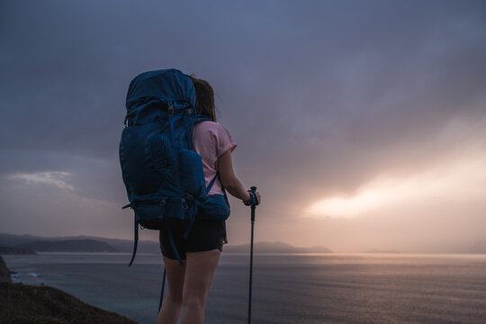 Anonymous hiker on shore at sunset time