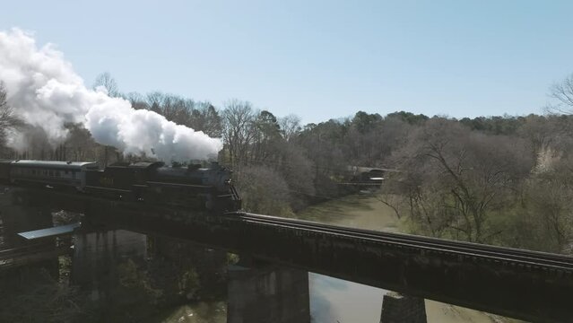 Aerial drone shot of a steam train engine moving over a bridge in Chattanooga, TN.