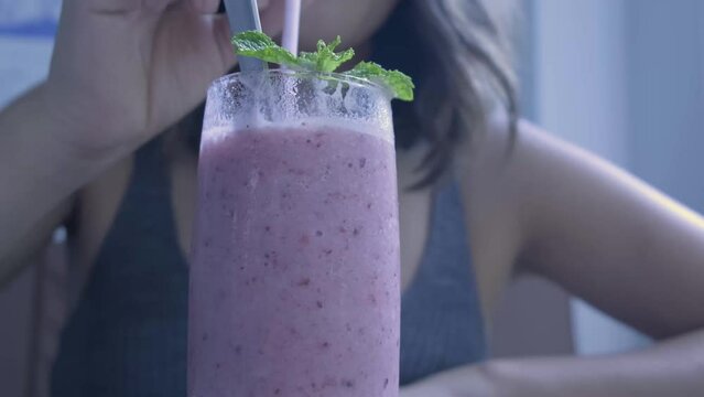 Female drinking from a smoothie in a restaurant in Thailand