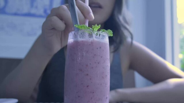 Panning in shot of a female model drinking a smoothie in a restaurant
