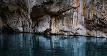 clean blue river with rocky banks at the bottom of a deep canyon