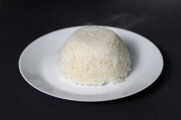 Fototapeta na wymiar rice on white plate over black background studio