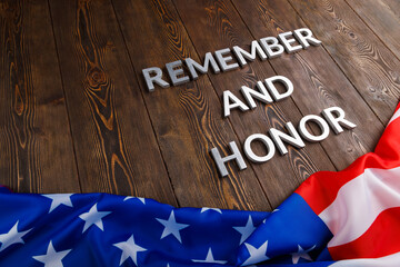 words remember and honor laid with silver metal letters on wooden background with USA flag...
